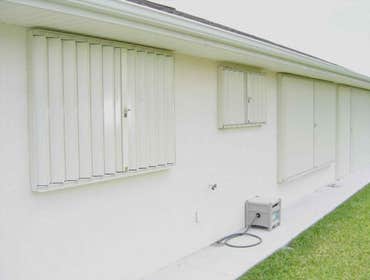 Accordian Shutters White Miami-Dade approved accordion shutters with key-locks and all hardware covering existing exterior windows and doors.