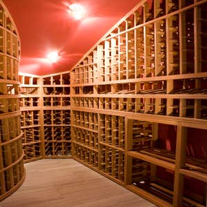 Project photos from Legacy Cellars Inc Custom African mahogany wine cellar within a room with a curved wall and sloping ceiling.