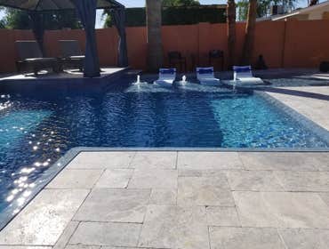 Custom Pools Wet edge pool in phoenix with sun shelf, splash pad and hardscape/landscape.