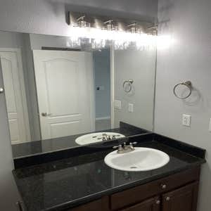 Bathroom vanity with dark granite countertop and modern light fixture