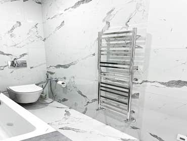 Modern Apartment. Marble Bathroom This contemporary bathroom renovation showcases a luxurious marble-inspired design with clean architectural lines and