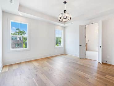 Spacious primary bedroom at 1135 Delmas Ave, East Nashville: tray ceiling, wide plank floors, and direct access to the ensuite by CJMC Build.