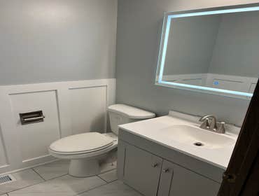 Photos by Goat Construction Group LLC #3 Total rehab of powder room with board & batten wall, LED mirror, tiled flooring, new toilet, vanity and fresh 