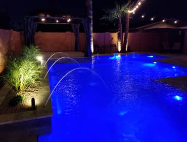 Custom Pools Wet edge pool in phoenix with sun shelf, splash pad and hardscape/landscape.