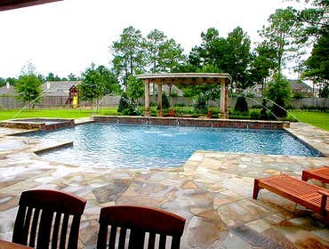Custom Swimming Pool Design - Cypress, TX This pool was designed to mesh with its environment. The copper pipe water feature and trough gives this back