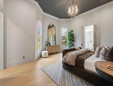 Primary bedroom with tray ceiling and chandelier in a full restoration and addition by CJMC Build in 12 South, Nashville.