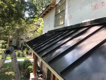 Photos by The Patchman Roofing Company #1 Installation of a dark-bronze standing seam metal roof over a patio built as an addition to a home.