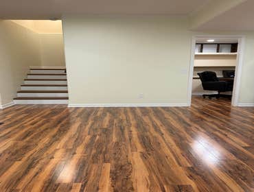Finished basement main living area with red oak stair treads, painted risers, and LVP flooring throughout. Crown molding and crisp white trim give the 