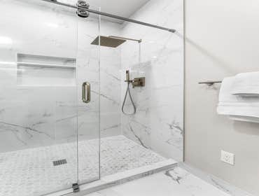 Pranav | Bathroom This bathroom remodel features polished marble-look tile throughout, accented by a hexagon shower floor for added texture. We install