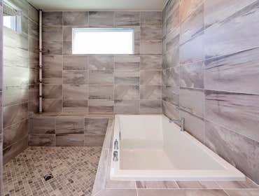 Brentwood Bathroom Remodel This bathroom features hardwood-looking tile flooring, white hardwood vanity with porcelain countertop and integrated sink. 