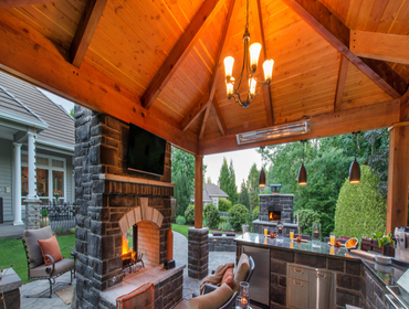 Photos by Paradise Restored Landscaping #1 Outdoor Living Space that includes a Covered Structure, Double Sided wood burning fireplace, Outdoor Kitchen