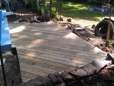 Pool Deck and stone wall A tree fell across this customers stone retaining wall and destroyed it. We rebuilt the wall and installed a deck that butted