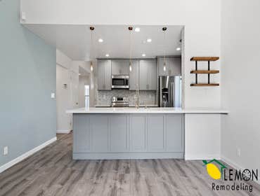 Modern kitchen with marble countertop, and available seating. Multicolored tile backsplash, integrated appliances, and recessed LED lights