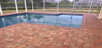 Pool Enclosure and Brick Pavers White Pool Enclosure with charcoal screen set over Euro Sunset, Yellow, Chocolate pavers.