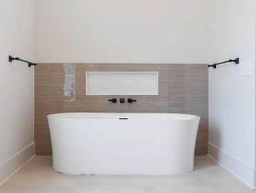 Serene bathing zone at 1135 Delmas Ave, East Nashville by CJMC Build: freestanding soaking tub with tiled niche and matte black fixtures.