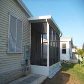 Screen Room and Slad Walkway White screen room with pan roof, gutters, and charcoal screen as well as slab leading to rear screen room and AC handler