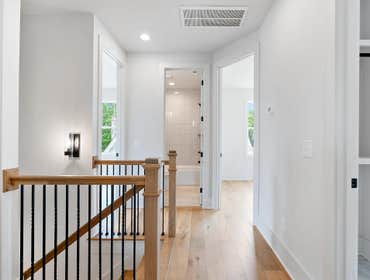 Light filled stair landing at 1135 Delmas Ave, East Nashville: oak handrail, iron balusters, and modern wall sconce by CJMC Build.