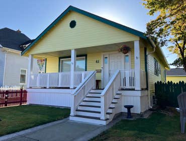 Covered front porch with gable roof integrated into existing home, featuring Trex decking, cedar-wrapped posts, and wide entry stairs.