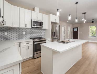 Bright Studio City kitchen remodel featuring a large quartz island, white shaker cabinets, subway tile backsplash, and stainless appliances.
