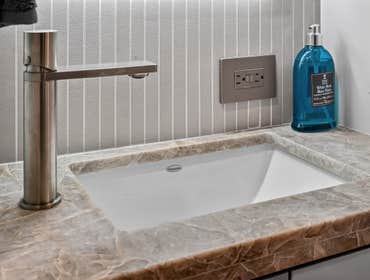 Bathroom Goals: That Backlit Glow A sleek, modern powder room featuring clean white cabinetry, a marble countertop, and a softly backlit mirror that ad