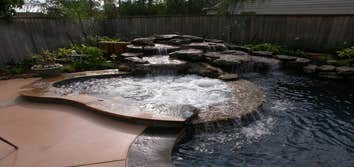 Rogers Custom Swimming Pool Project A unique rock beam stretches from end to end to provide a natural shape for shrubbery and seasonal color. The rock