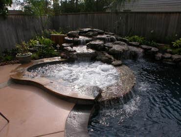 Rogers Custom Swimming Pool Project A unique rock beam stretches from end to end to provide a natural shape for shrubbery and seasonal color. The rock