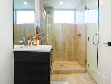 Subtle Toned Bath Design The bathroom is mostly white, with a subtle Cremino yellow bathroom floor and wall tiles giving the space a comfortable and tr