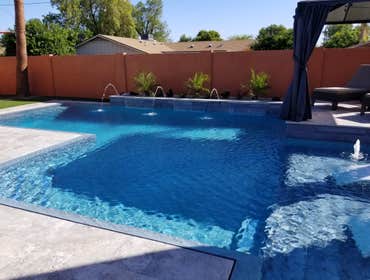 Custom Pools Wet edge pool in phoenix with sun shelf, splash pad and hardscape/landscape.