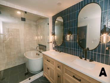 Midnight Serenity- Bathroom Remodel This bathroom remodel combines bold style with earthy elegance. The main area is anchored by deep blue wall tiles, 