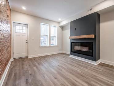 Modern Fireplace Feature Wall: A sleek, black accent wall with a mounted wood mantel and an electric fireplace adds warmth and style to the room.