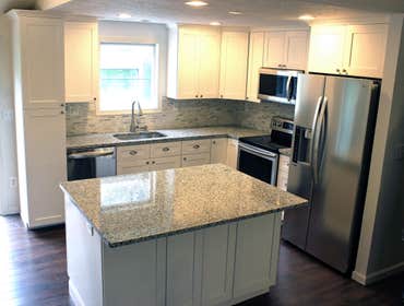 Shaker style with wood floors. Removed some walls to open up the space. Install hand scraped hardwood floors to bring out the white in the cabinets.