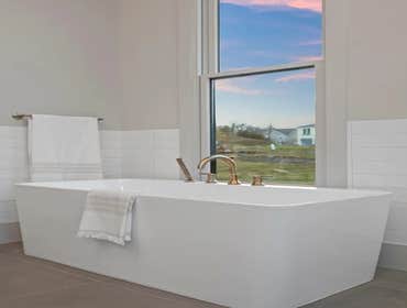 Freestanding tub with large window and brass fixtures as part of the primary suite renovation by CJMC Build in 12 South, Nashville.