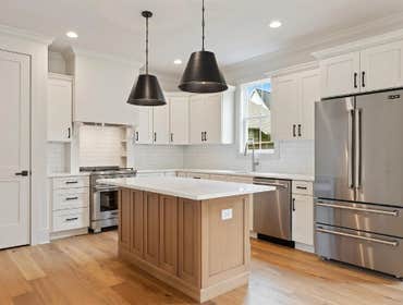 Center island with quartz top and pendant lights anchors the chef's kitchen at 2703 Bronte Ave, Nashville by CJMC Build.