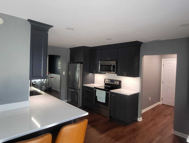 Great Mills Kitchen Renovation This stunning kitchen features bold, dark cabinetry paired with sleek white countertops for a modern and elegant contras