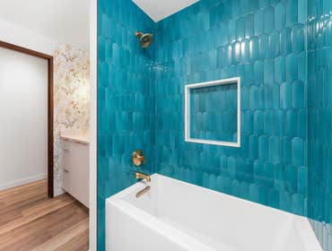 Kate | Full Bathroom This playful and elegant bathroom remodel features a floral wallpaper that brings warmth and charm to the space. The bold teal sca