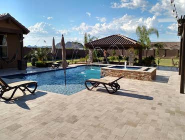 Custom Pools Wet edge pool in phoenix with sun shelf, splash pad and hardscape/landscape.