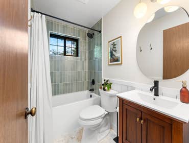 Cody & Katie | Guest Bathroom This guest bathroom remodel blends warm natural elements with timeless design. Soft green shower tile, pebble-style floor