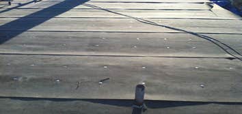 Flat Roof Ponds Water But Doesn't Leak: 10 Yr Guarantee!! In a perfect world there would have been money in the budget to create a slope on this home..