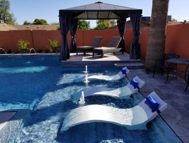 Custom Pools Wet edge pool in phoenix with sun shelf, splash pad and hardscape/landscape.