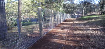 Fence Enclosure for Rescued Cats 850' of 6' high 2" x 4" fence with 5 gates. Project includes underground gopher wire along fence line to prevent coyo