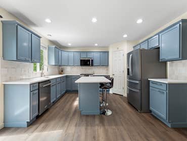 Chiranjeevi and Sindhu | Kitchen This kitchen remodel features soft blue cabinetry paired with sleek white quartz countertops and a functional center i