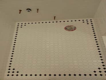 Full bathroom remodel Subway tile walls with stone floor. Mosaic bathroom floor with decorative black diamonds. Chair rail finishes wainscot and contin