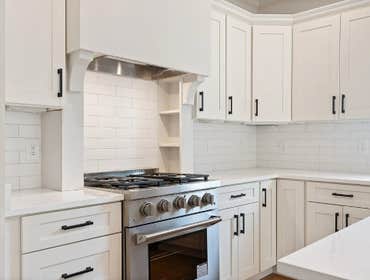 Pro-style range and custom hood with subway tile backsplash in the chef's kitchen at 2703 Bronte Ave, Nashville by CJMC Build.