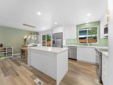Kate | Kitchen We remodeled this kitchen with sleek white cabinets, a matte black sink, and a striking gold faucet. Soft green tile adds color and warm