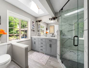 James and Lisa | Master Bathroom This elegant bathroom remodel blends modern design with timeless charm. The spacious walk-in shower is framed in glass