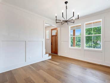 Formal dining at 1135 Delmas Ave, East Nashville: custom wall millwork, wide plank flooring, and a modern chandelier by CJMC Build.
