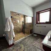 Custom Shower Fully tiled shower with bench seating and river rock floor. Separate rain shower head on the wall above the door.