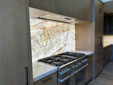 Martis Camp, Onyx slab kitchen counters with backlit splash Natural onyx slab counters with waterfall island edge and backlit splash.