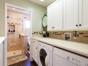 Cambrian Bath & Craftroom Natural travertine shower tiles and porcelain wood floor tiles work together to enhance the cozy bathroom/laundry room combo 