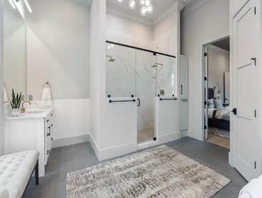 Primary bath with double shower, marble-look tile, and brass accents completed by CJMC Build in 12 South, Nashville.